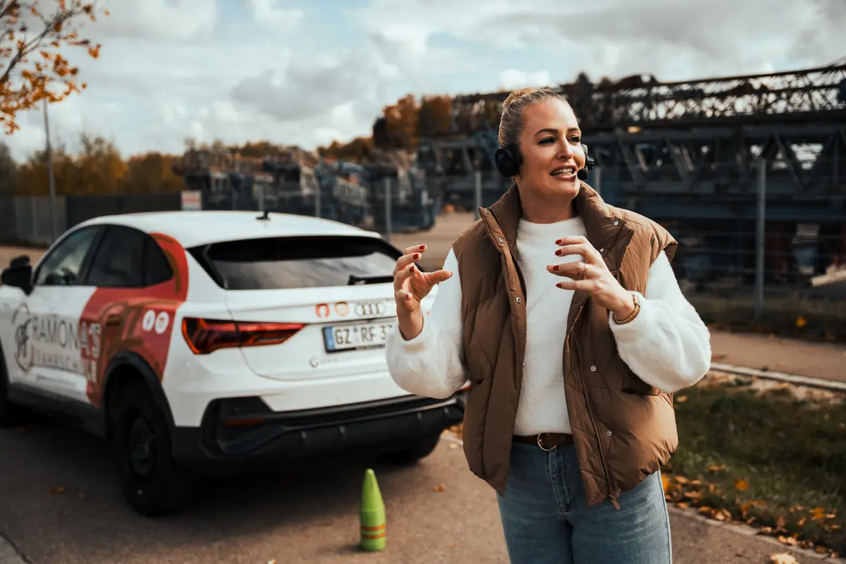 Ramona Frischholz mit Headset bei einer Übung neben dem Fahrschulauto